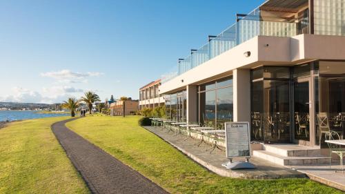 a building with tables and chairs next to the water at Millennium Hotel & Resort Manuels Taupo in Taupo