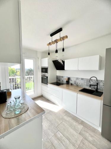 une cuisine avec des armoires blanches et un comptoir dans l'établissement Appartement proximité Strasbourg, à Lingolsheim