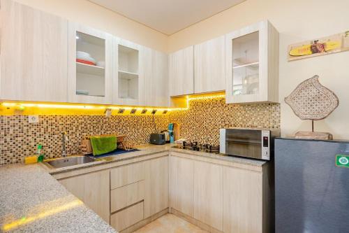 une cuisine avec des armoires blanches et un réfrigérateur noir dans l'établissement Villa Naga, pool, Kitchen, terace and garden, à Kerobokan