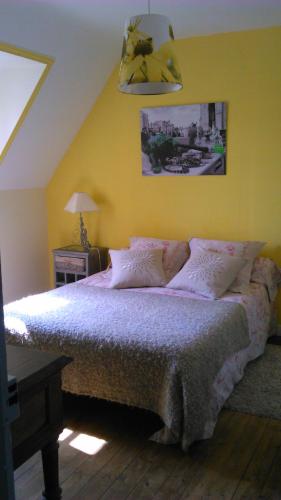 une chambre avec un lit avec un mur jaune dans l'établissement Chambre d'hôtes La Maison du Neuilly, au Conquet