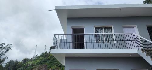 a white building with a balcony with a window at Heath Cote in Ooty