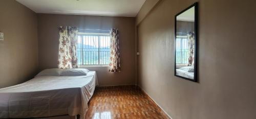 a small bedroom with a bed and a mirror at Heath Cote in Ooty