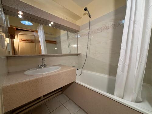 ein Badezimmer mit Waschbecken, Spiegel und Badewanne in der Unterkunft Résidence Atrey 403 Clés Blanches Courchevel in Courchevel