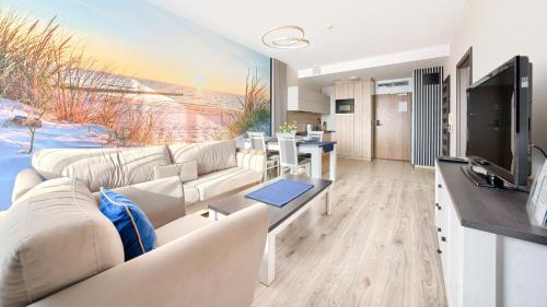 a living room with a white couch and a television at Olympic Park I, Sun & Snow in Kołobrzeg