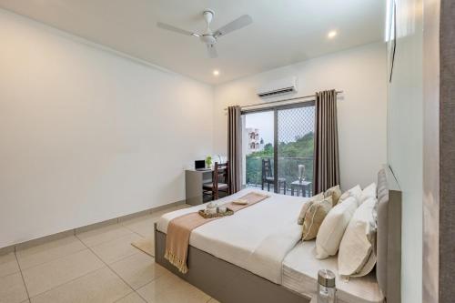 a white bedroom with a large bed and a window at Alaya Stays with Balcony & Hill View - Lake City Heights in Udaipur