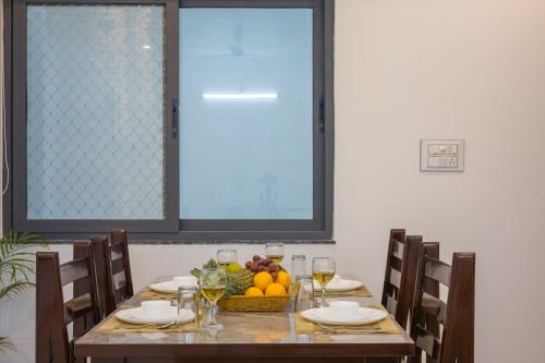 a table with a basket of fruit and wine glasses at Alaya Stays with Balcony & Hill View - Lake City Heights in Udaipur