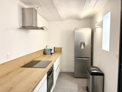 Il comprend une cuisine avec un réfrigérateur en acier inoxydable et des murs blancs. dans l'établissement Appartement confortable pour 4 voyageurs, à Roubaix