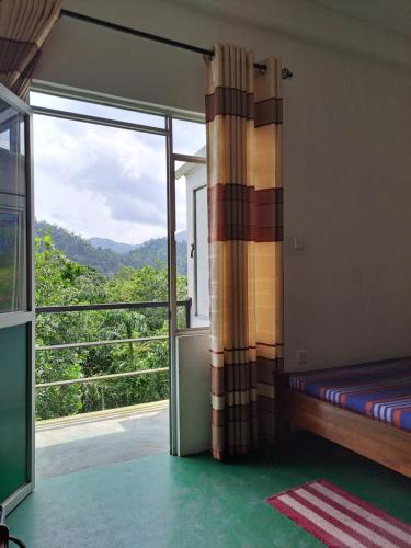 a room with a bed and a large window at 38 guest house in Kitulgala