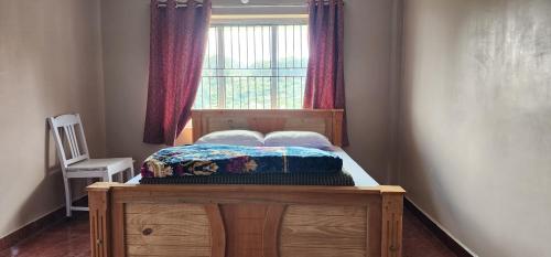 a small bed in a room with a window at Heath Cote in Ooty