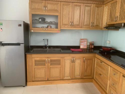 a kitchen with wooden cabinets and a stainless steel refrigerator at X-Stay Thư Trung in Hai Phong