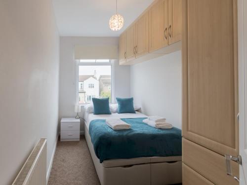 a bedroom with a bed with blue pillows and a window at Pass the Keys Cosy Flat in Leigh Sea View in Southend-on-Sea