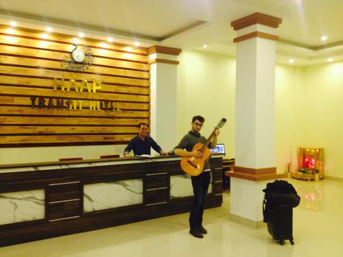 a man holding a guitar in front of a bar at HAAP Transit Hotel in Noi Bai