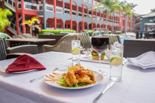 Una mesa con un plato de comida y una copa de vino. en Seaview Gardens Hotel, en Kololi