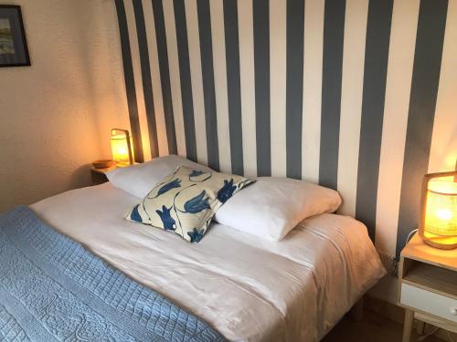 a bed with two pillows and a striped wall at La Gimoniere in La Barre-de-Monts