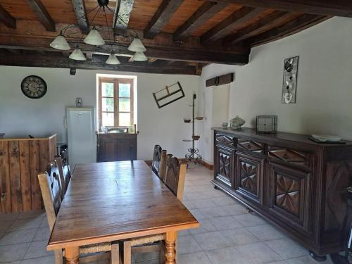 une salle à manger avec une table en bois et une cuisine dans l'établissement La Maison des Renouillers, à Éguilly