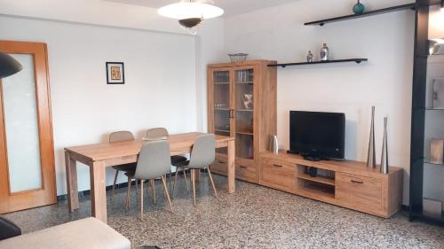 ein Esszimmer mit einem Holztisch und einem TV in der Unterkunft Carlota y Vaquero house in Vinarós