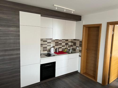 a kitchen with white cabinets and a sink at APARTMAN broj 9, SUNČANI BREG RESORT & SPA in Kopaonik