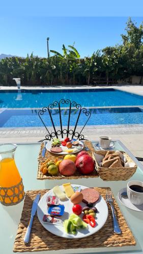 a table with plates of food on a table near a pool at The Horse Farm Hotel in Kérynia