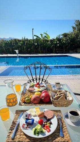 a table topped with plates of food next to a pool at The Horse Farm Hotel in Kérynia