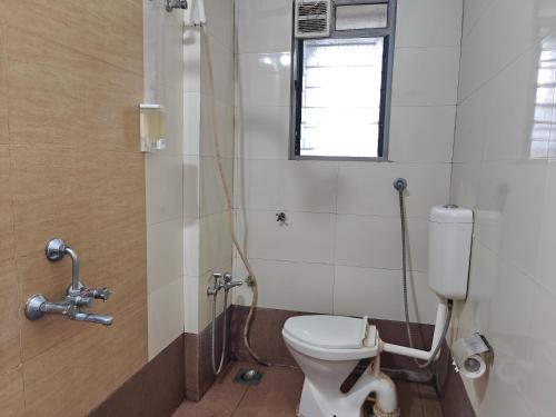 a bathroom with a toilet and a window at Chandralok Service Apartments in Kolhapur