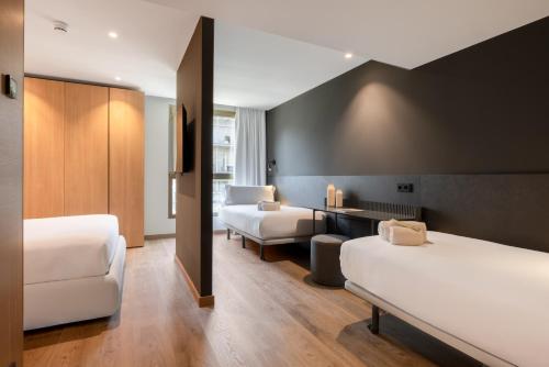 a hotel room with two beds and a desk at Hotel SB Win 4 Sup in Sant Feliu de Llobregat