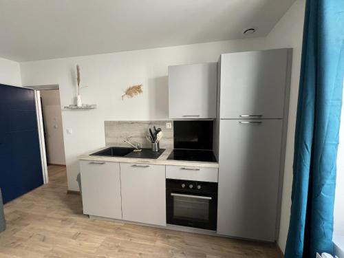 La cuisine blanche est équipée d'un réfrigérateur et d'un évier. dans l'établissement Oasis Urbaine - 2-4p centre-ville, Place Dalton, à Boulogne-sur-Mer