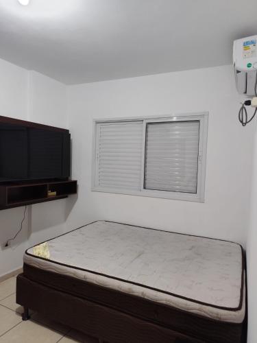 a bed in a room with a tv and a mattress at Apartamento perto da praia com ar condicionado in Praia Grande