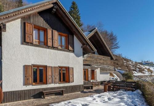 a house with wooden windows and benches in the snow at Panoramic House Carnia ,3 badroom chalet Ligosullo - Treppo Carnico - Paluzza - Zoncolan in Ligosullo