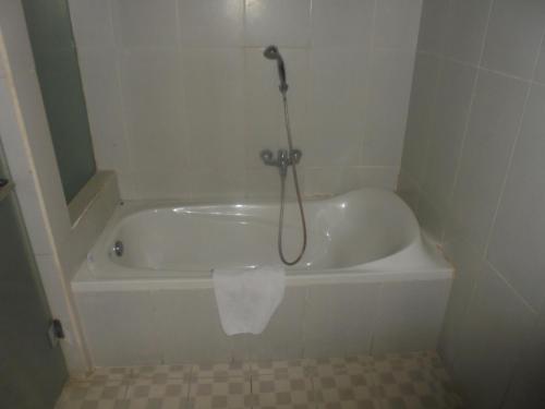 a white bath tub with a shower in a bathroom at Biyukukung Suite & Spa in Ubud