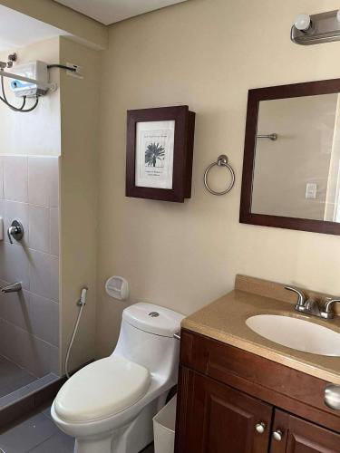 a bathroom with a toilet and a sink and a mirror at Belle's Staycation in Cebu City