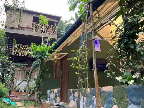 a green house with a porch and a balcony at Ela Forest Stay in Kannādi