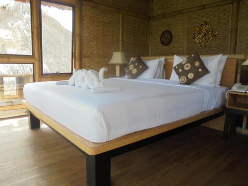 a large white bed in a room with a window at Biyukukung Suite & Spa in Ubud