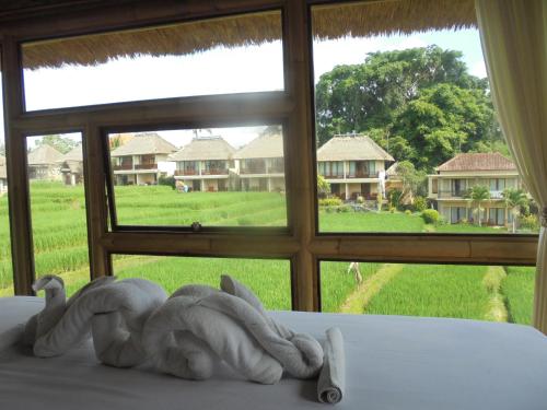 a statue of a person sitting on a bed in front of a window at Biyukukung Suite & Spa in Ubud
