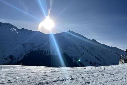 a sun is shining on a snow covered mountain at Lovely appartment in Rueras bei Sedrun in Rueras