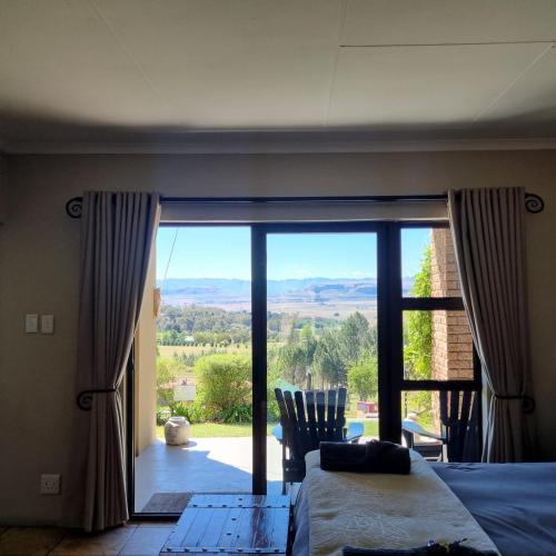 a bedroom with a bed and a large glass door at The Fat Mulberry Guest Farm in Fouriesburg