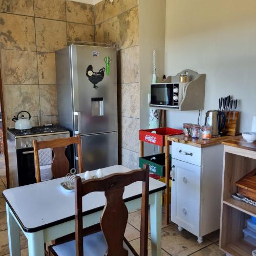a kitchen with a stainless steel refrigerator and a table and chairs at The Fat Mulberry Guest Farm in Fouriesburg