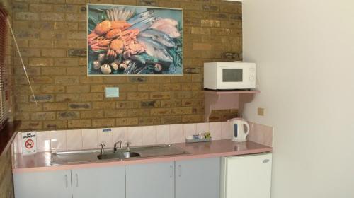 una cocina con fregadero y una pintura en la pared en Tooleybuc Motel, en Tooleybuc