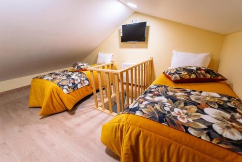 a room with two beds and a tv on the wall at Casa 14 in Sabugal