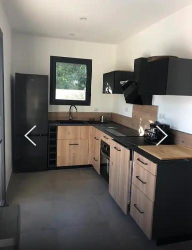 une cuisine avec des armoires en bois, un évier et une fenêtre dans l'établissement Villa Ucellu sur 600 m2 avec accès mer privilégié et piscine privée chauffée, à Sainte-Lucie de Porto-Vecchio