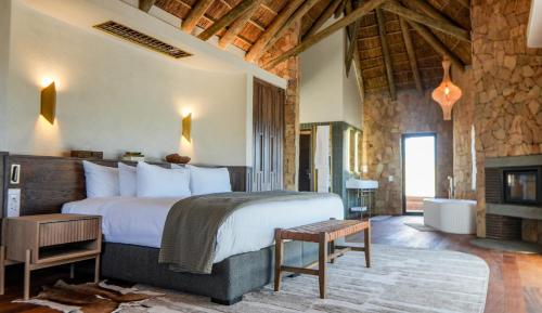 a bedroom with a large bed and a fireplace at Aquila Private Game Reserve & Spa in Touwsrivier