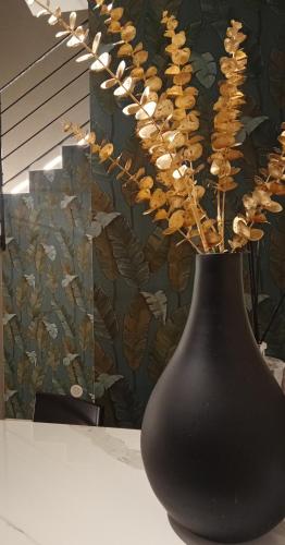 a black vase sitting on a table with flowers at Narciso boutique apartment in Acireale
