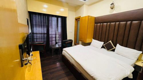 a bedroom with a large bed and a window at Hotel New Holiday in Bhilwara