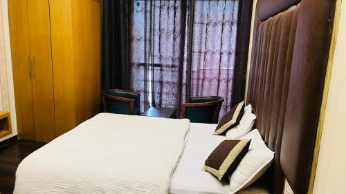 a bedroom with a bed with two chairs and a window at Hotel New Holiday in Bhilwara