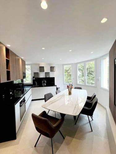 une grande cuisine avec une table et des chaises blanches dans l'établissement Appartement 4 pièces luxueux, à Cannes