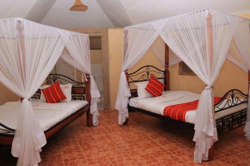 a bedroom with two beds with mosquito nets at ELANGATA OLERAI LUXURY TENTED CAMP in Narok