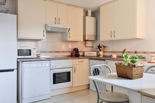 a kitchen with white appliances and a table with chairs at Acogedora con Jardín y Chimenea by CABANA Rentals in Navas de San Antonio
