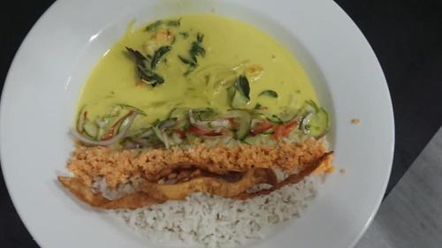 a white plate with a piece of fish with sauce and rice at Nagara Lake Glamping Resort in Hambantota