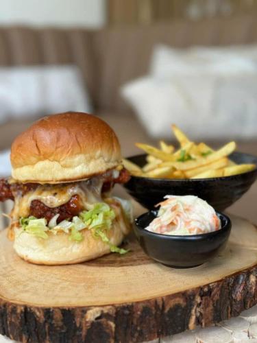 a sandwich on a cutting board with a bowl of fries at Nagara Lake Glamping Resort in Hambantota