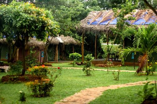 a garden with a hut with trees and plants at Nagara Lake Glamping Resort in Hambantota