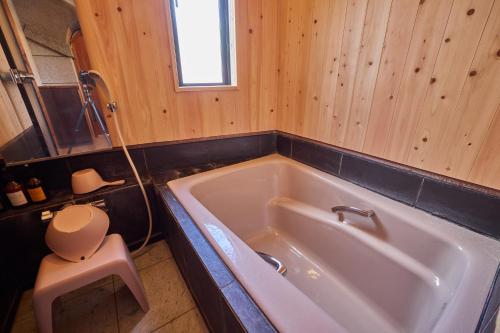 a bathroom with a white tub in a wooden wall at 博世庵 in Nishikatsuracho